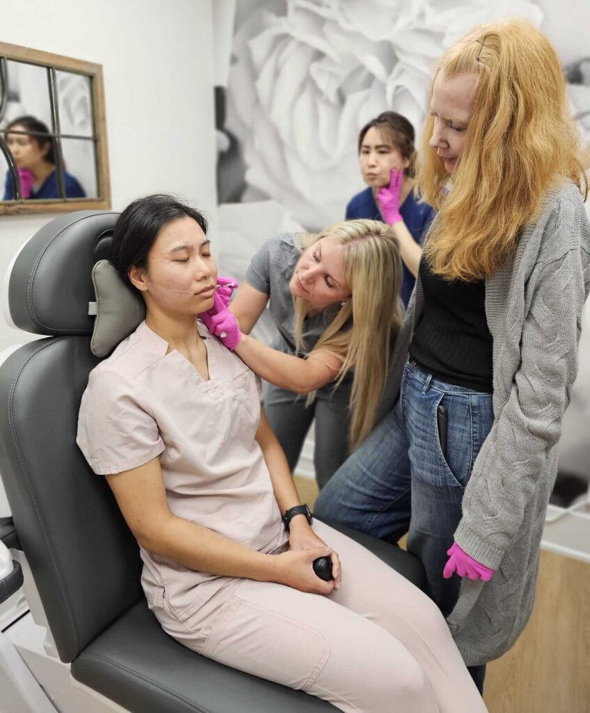 Trainees gathered around a live model during a small-group injection training session