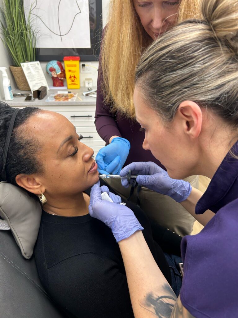 An instructor and trainee performing a filler injection on a model